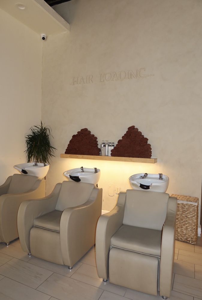 The wash lounge at Evolve Salon with plush chairs beneath the words Hair Loading