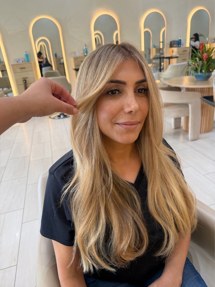 Warm golden blonde hair with darker roots, straight with face-framing layers