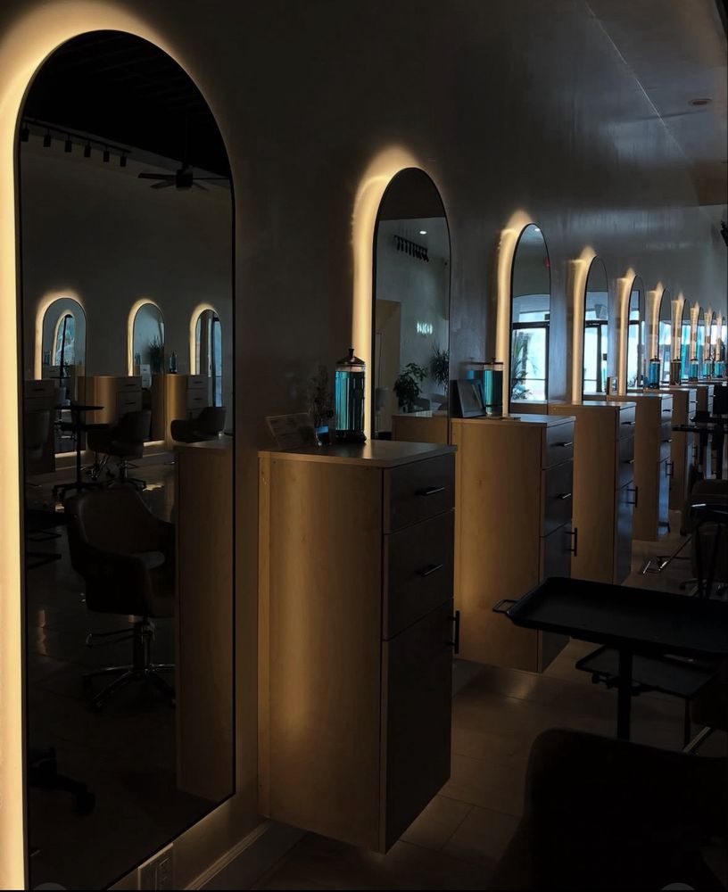 Evolve Salon styling stations glowing after dark, each arched mirror ringed with warm backlight