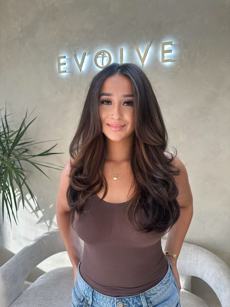 Long dark brown hair with subtle warm highlights styled in voluminous waves